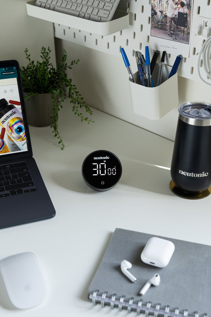 Black digital focus timer displaying 30 minutes on white desk near laptop and wireless earbuds, emphasizing nootropics use. - Neutonic - Focus Timer